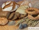Bochenki chleba razowego i pokrojone kromki. Dekoracja z kłosów pszenicy, ziarna słonecznika i soli wielickiej